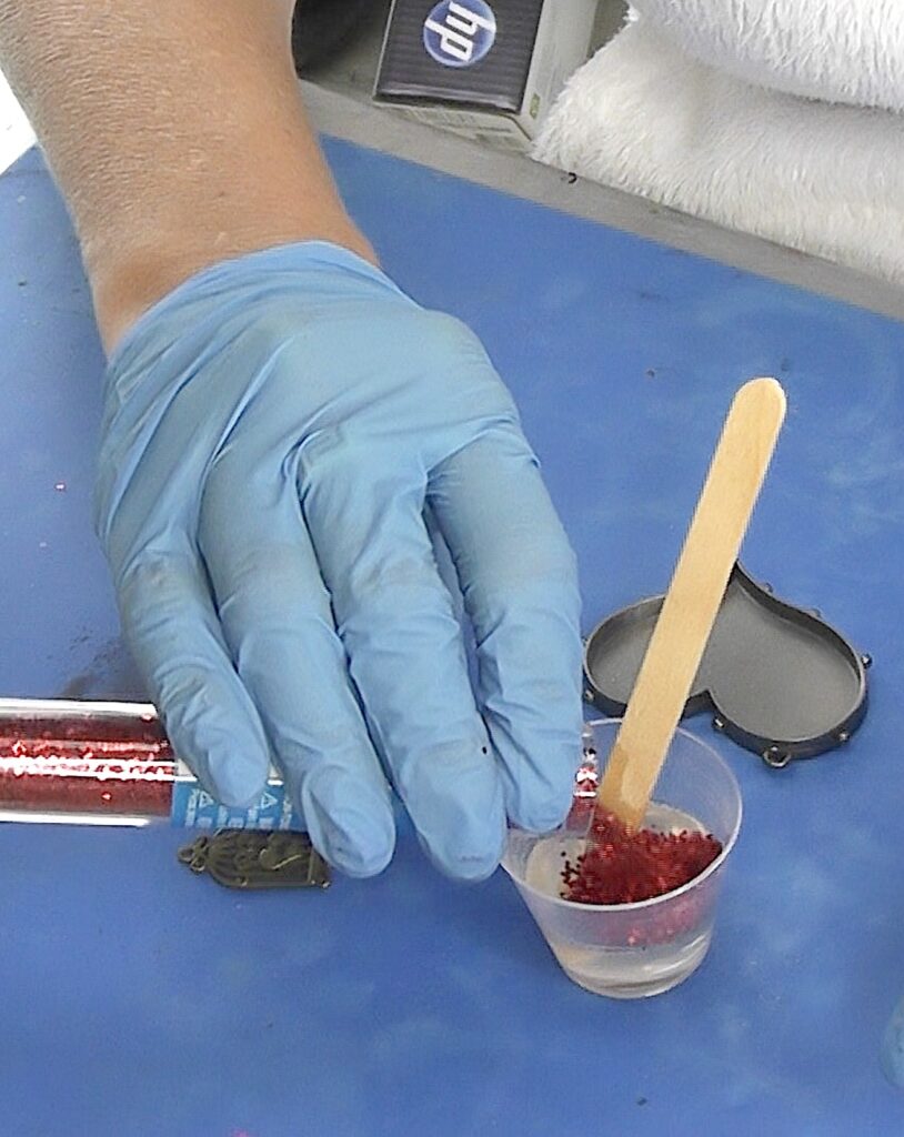 Pour chunky red glitter into resin for heart pendant