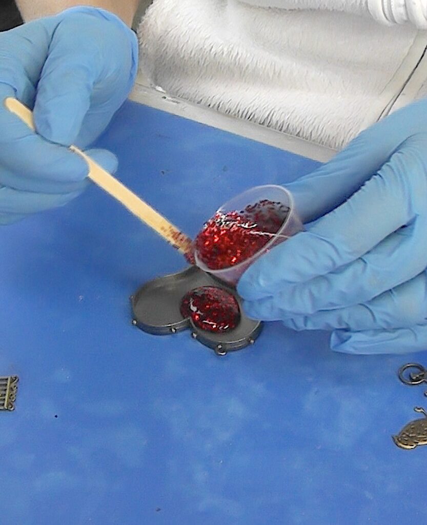 Drip red glitter resin into the heart pendant bezel