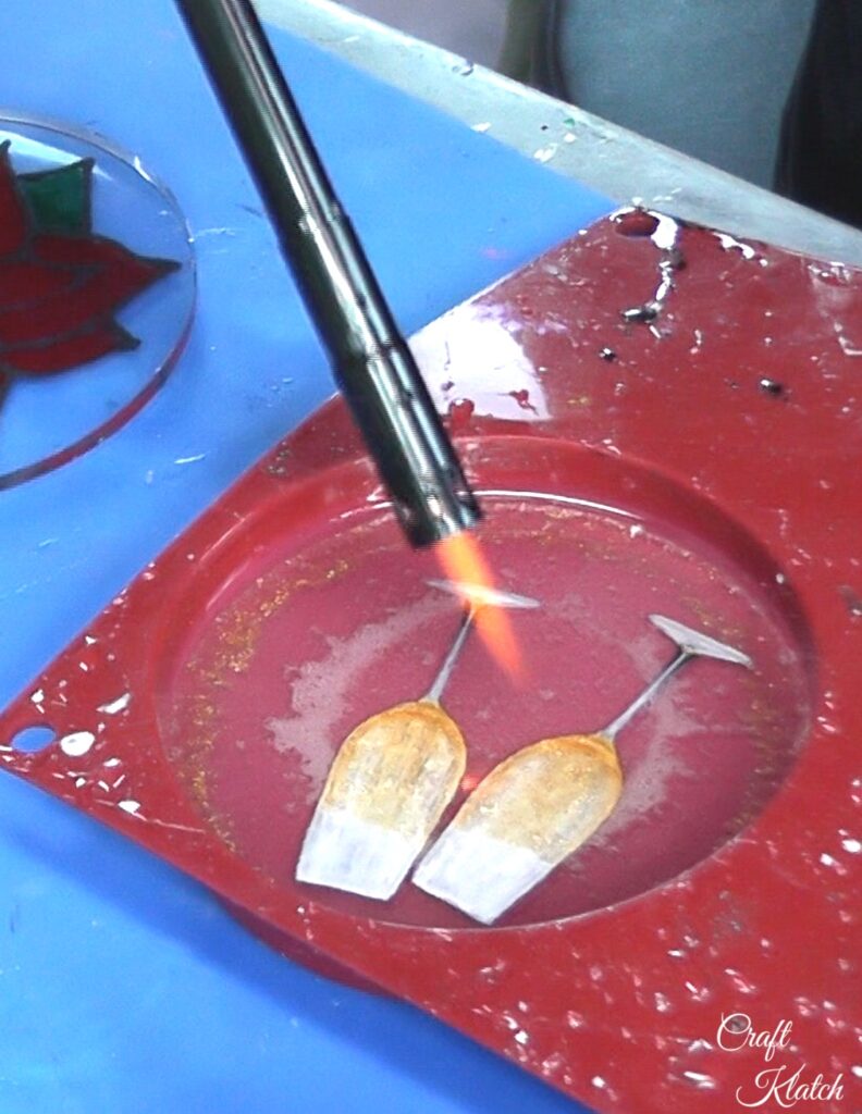 Use lighter to pop bubbles in resin of the New Years Eve champagne cocktail coaster