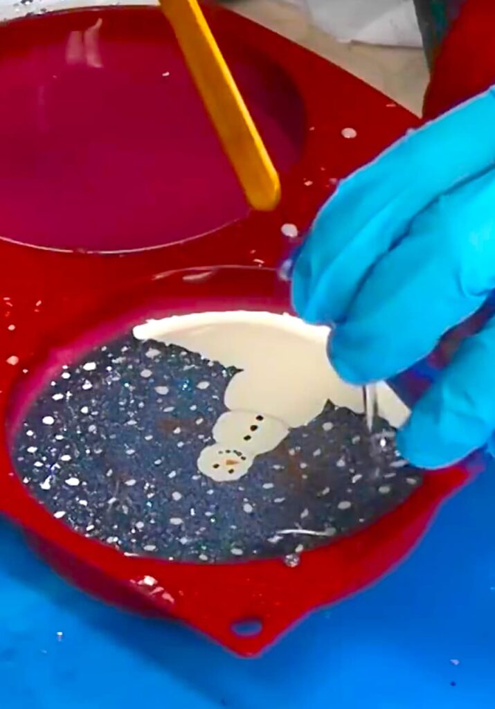 Pouring resin over the how to paint on resin snowman coaster DIY