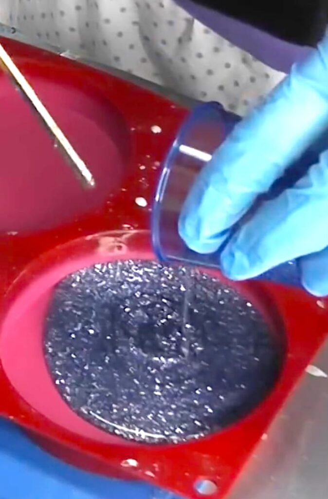 Pouring the glittered background resin layer for the snowman coaster