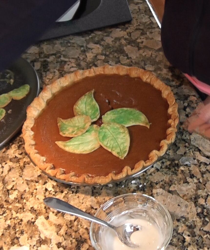 Placing baked green leaves on pumpkin pie