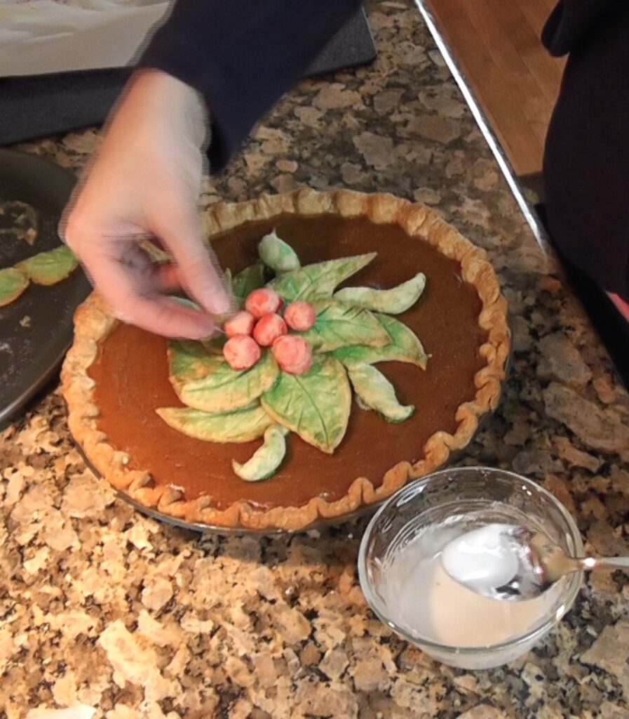 Placing red dough berries on pumpkin pie