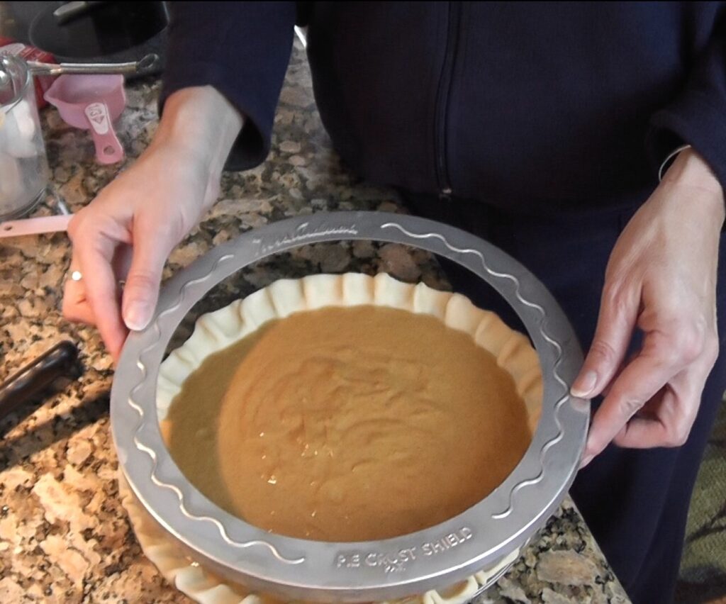 Putting crust shield onto pie crust