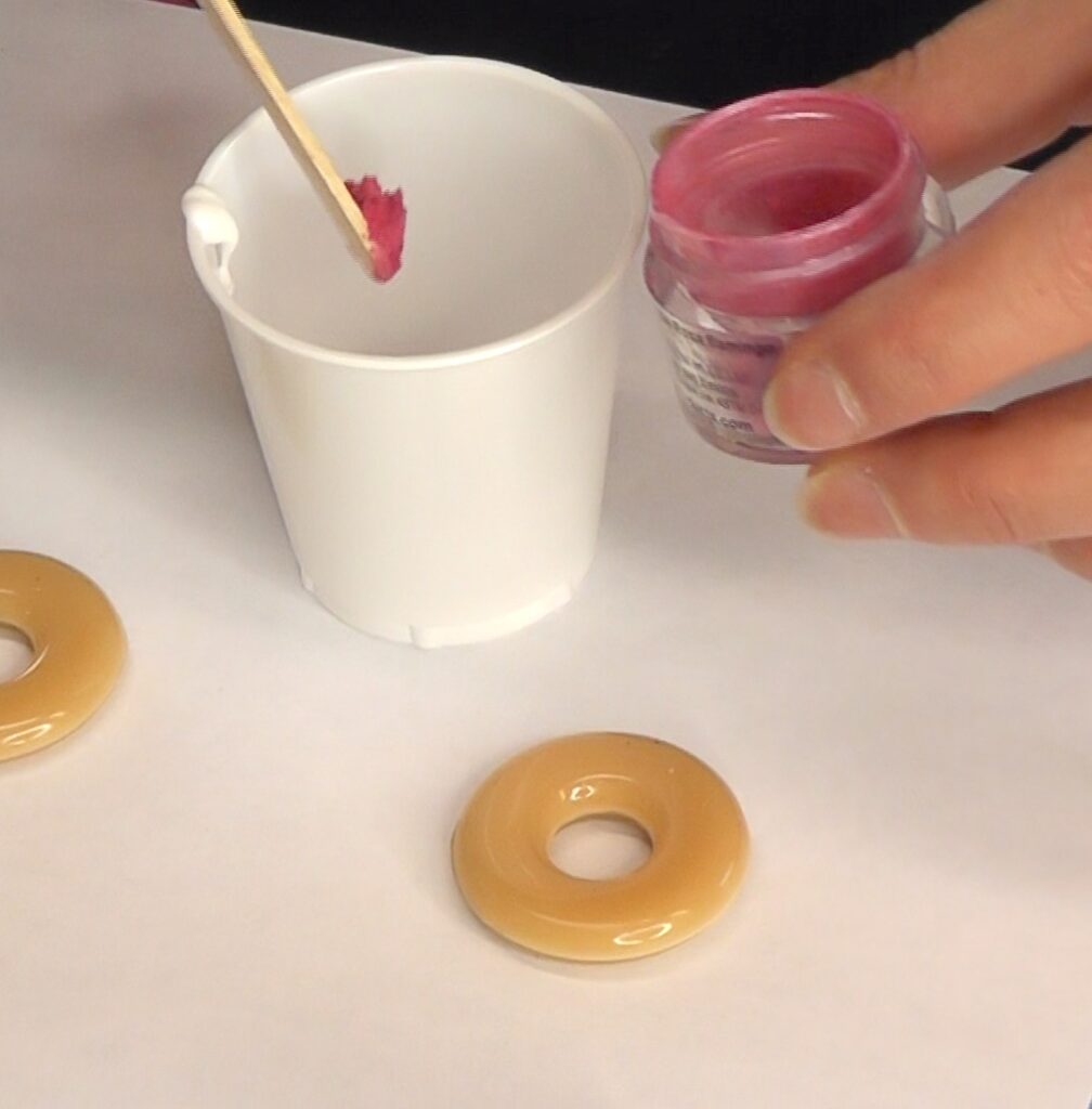 Mix glue and pink pigment in a cup to make frosting