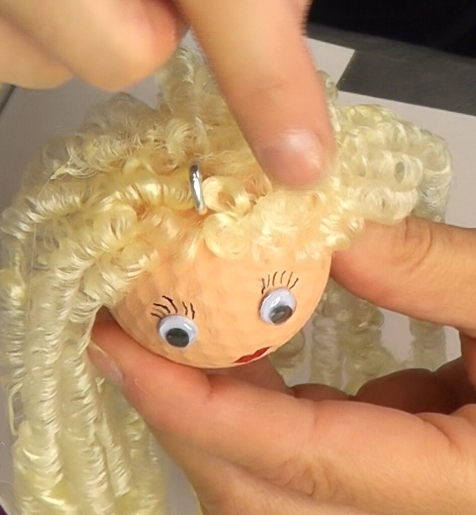 Glue on curly blonde doll hair to the painted golf ball. The princess project is starting to take shape.