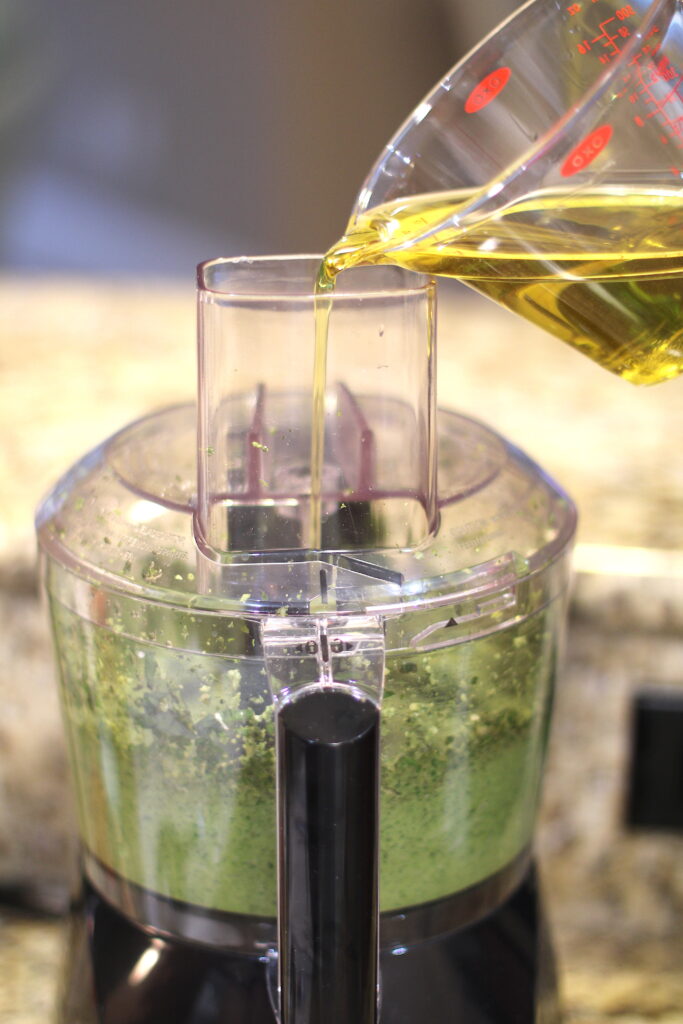 Pour olive oil into food processor for basil pesto recipe