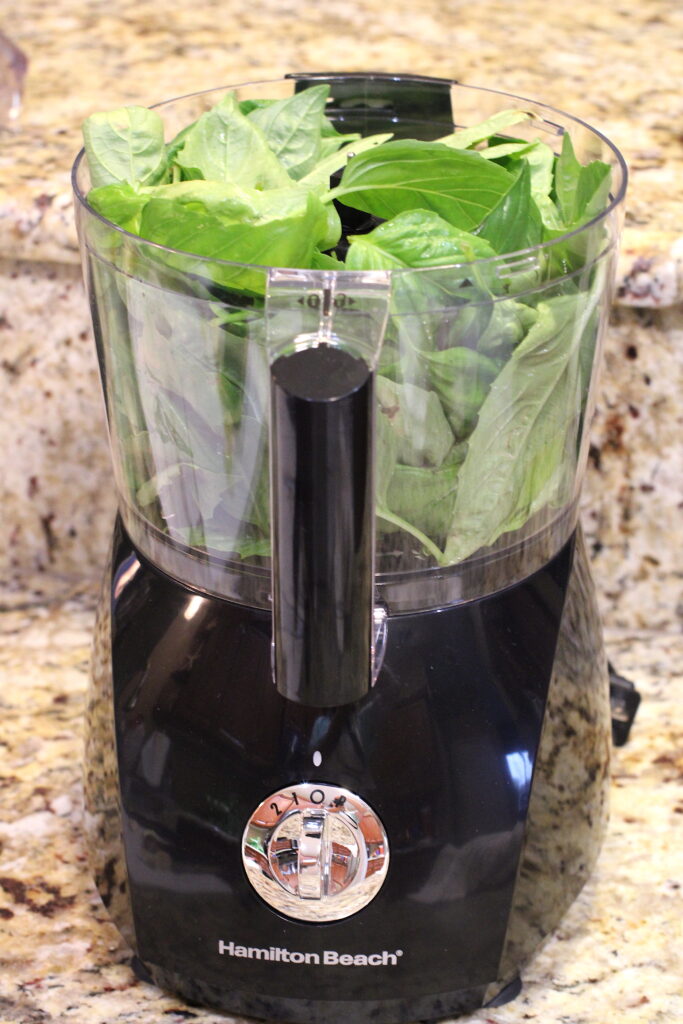 Food processor filled with fresh basil
