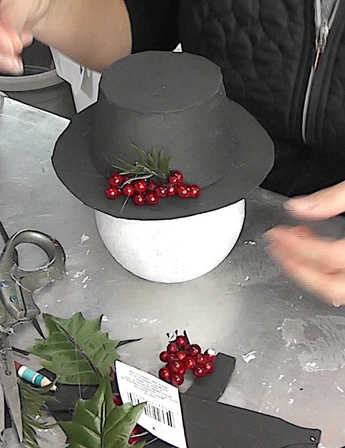 Add greens and red berries to the hat
