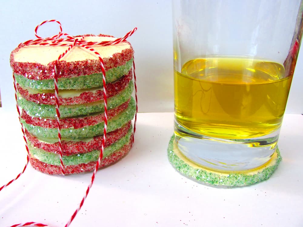 Easy sugar cookie Christmas coasters stacked and tied with red and white bakers twine with a glass next to it on one of the coasters