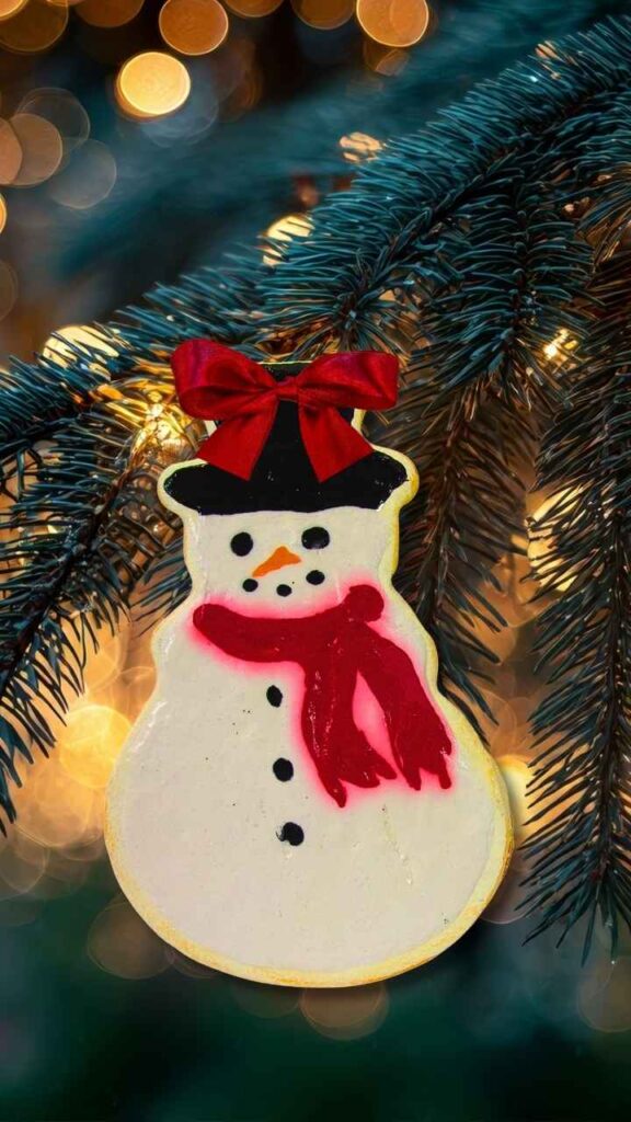Snowman cookie ornament hanging from a Christmas tree