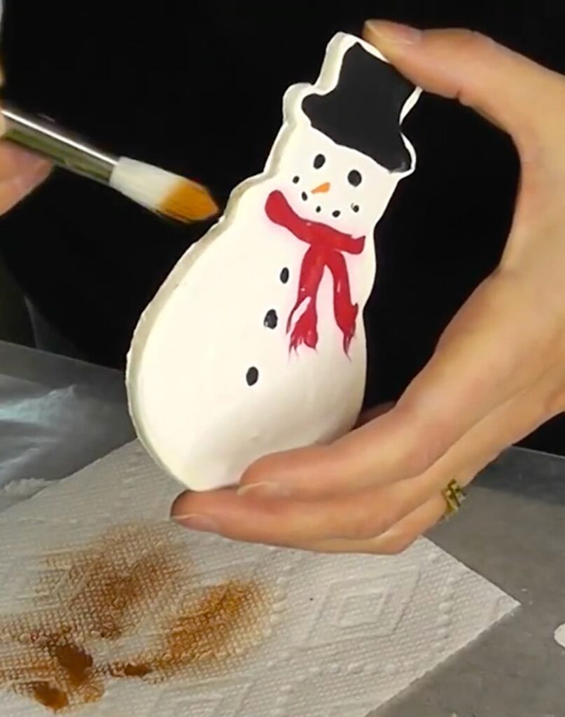 Brushing baked edges onto the snowman Christmas cookie