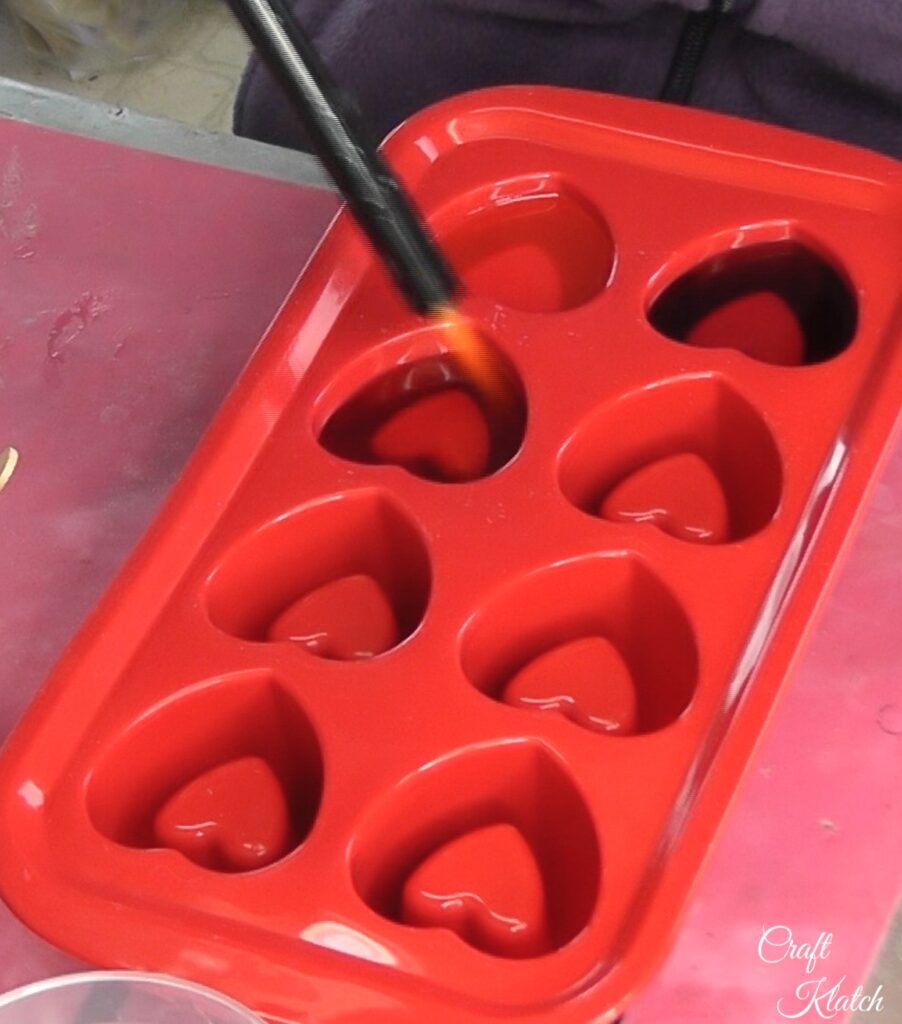 Use lighter to pop bubbles in resin hearts