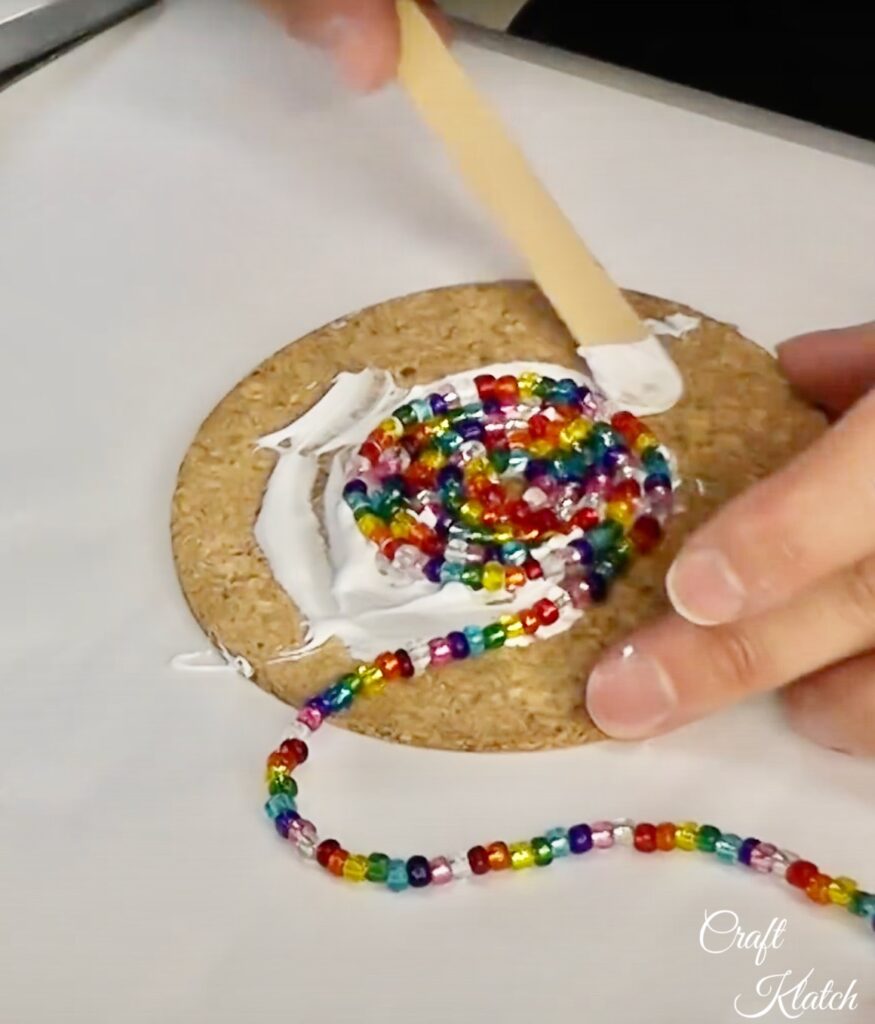 Spreading glue on cork round to glue on glass beads 