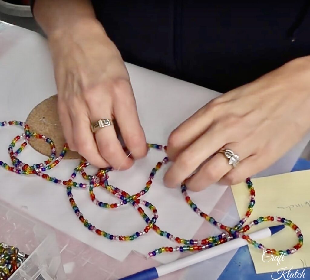 Stringing rainbow colored glass beads on fish line