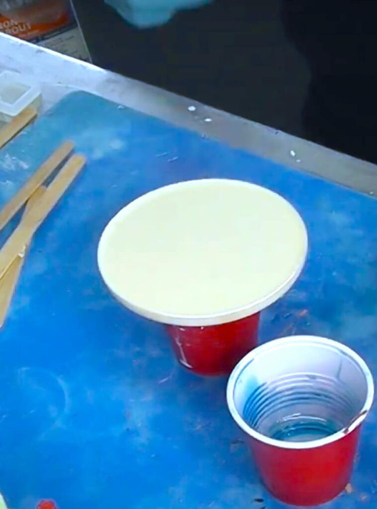 The white coaster base is raised up on a plastic cup