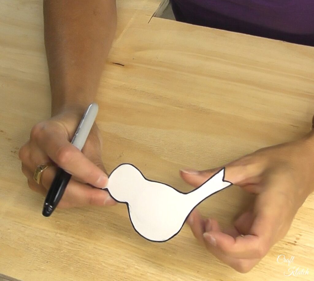 Holding paper bird template out of paper with plywood underneath