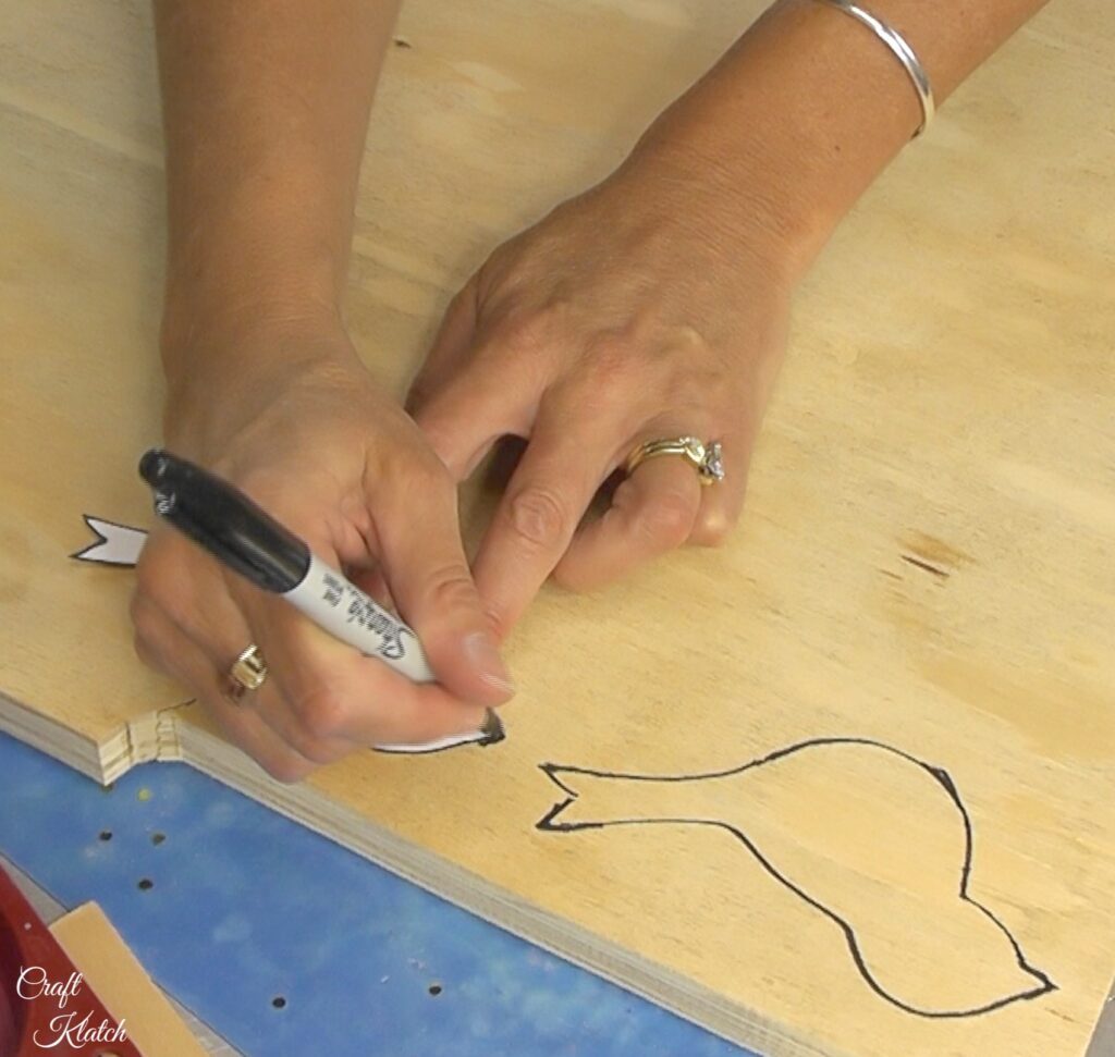 Tracing bird template onto plywood with a black marker