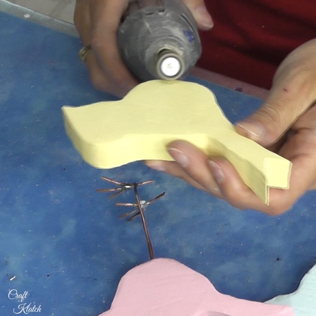 Using rotary tool to sand edges of yellow bird