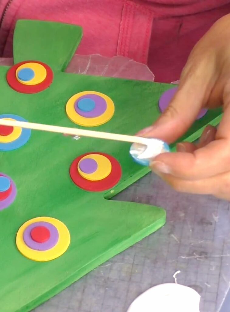 adding glue to the back of the painted wood circles
