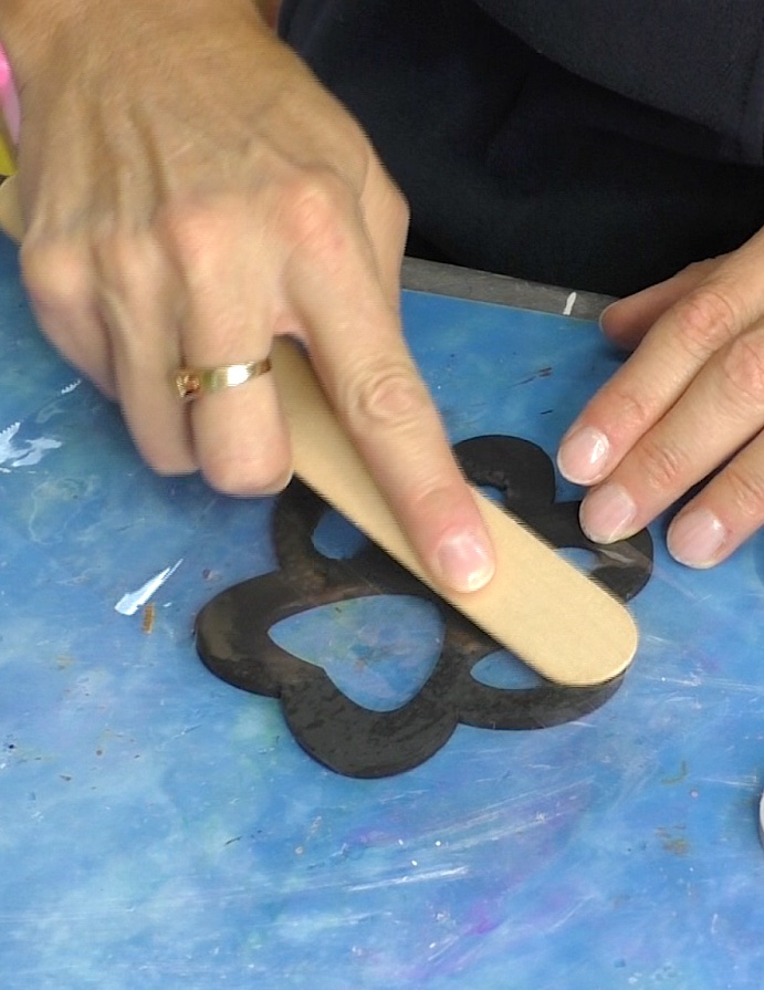 burnishing packing tape on the back of the pet paw coaster cutout for the diy crafts for pet lovers