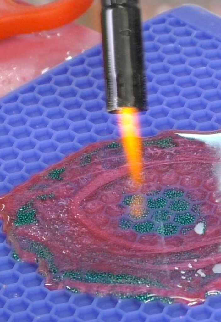 Use lighter to pop the bubbles on the free form resin coaster