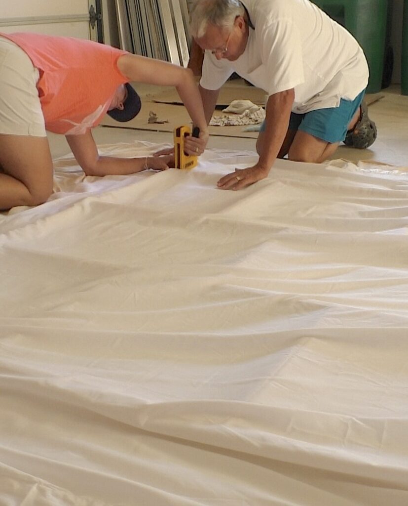 Stapling white sheet on wood frame to create sea turtle large wall art