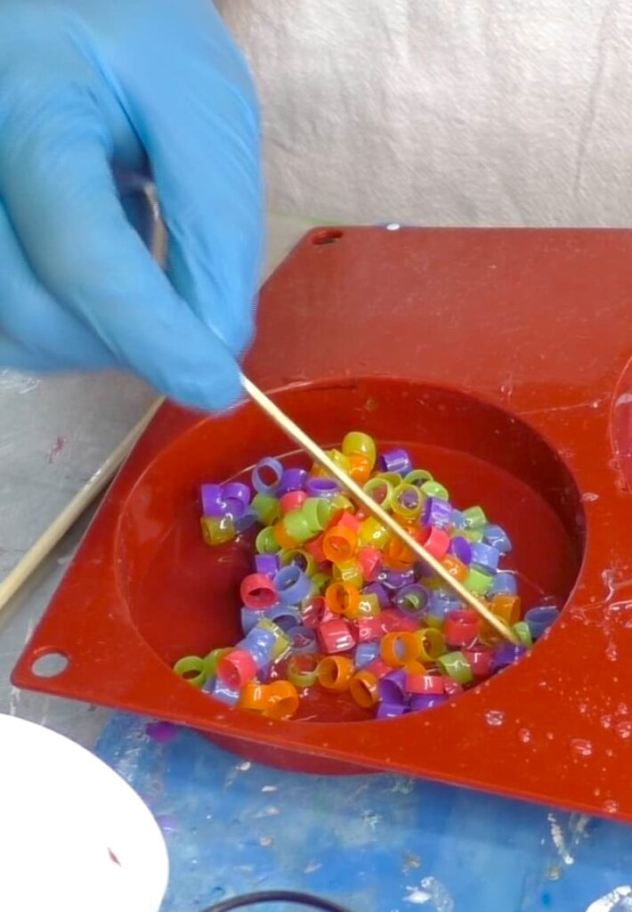 Pouring resin mixed with straw pieces into a round coaster mold and moving them around