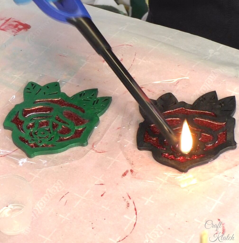 Use a lighter to pop the bubbles in the red glitter resin