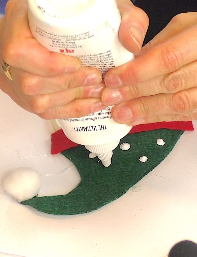 Add clear drying glue dots to the snowman craft cap