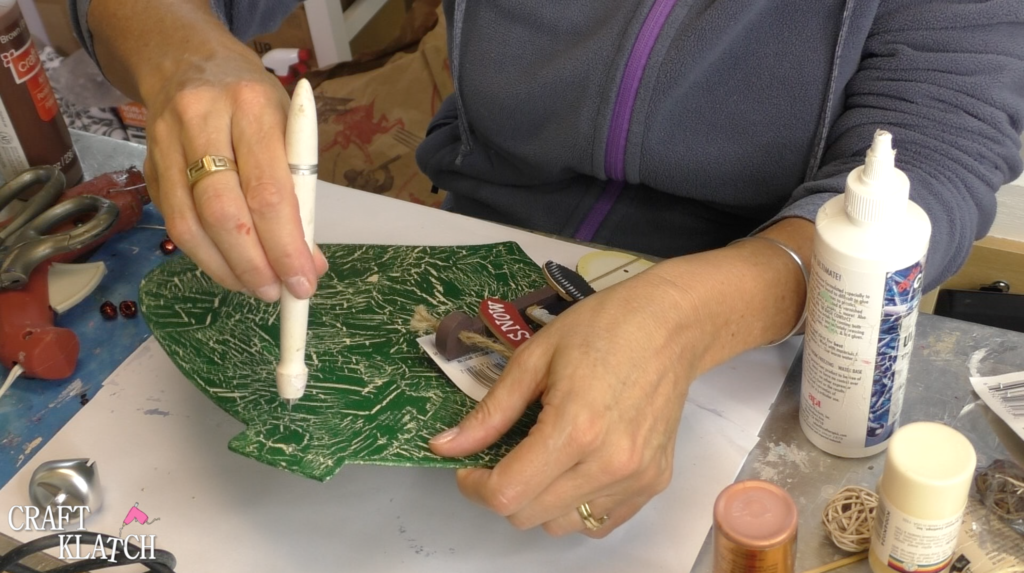 Using craft knife to clean out the hole where the string goes on the ornament that was covered with paint