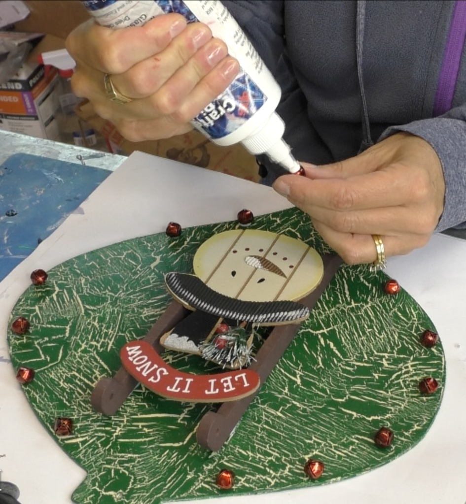 Gluing red jingle bells onto ornament