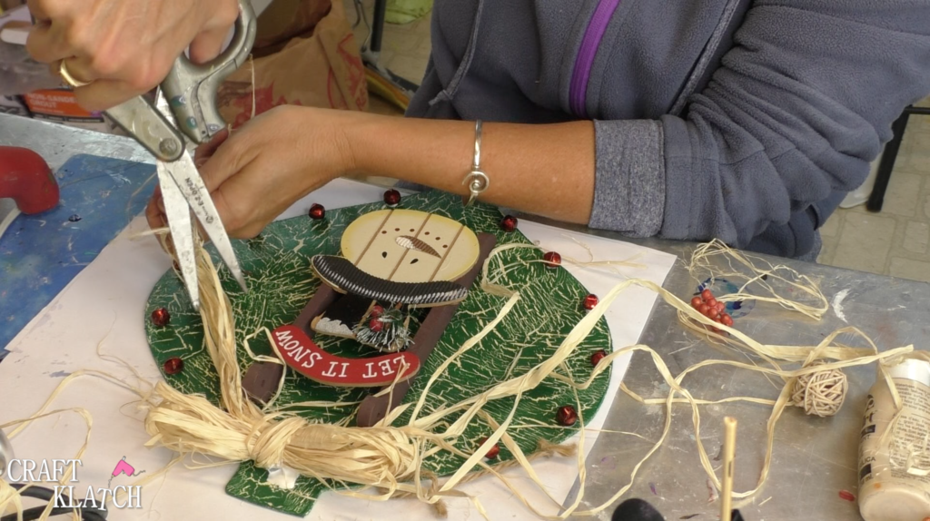 Trimming ends of raffia bow with scissors