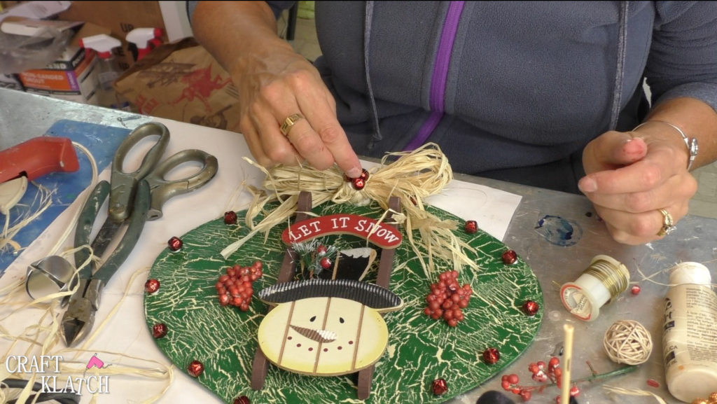 Adding the jingle bells to the raffia bow