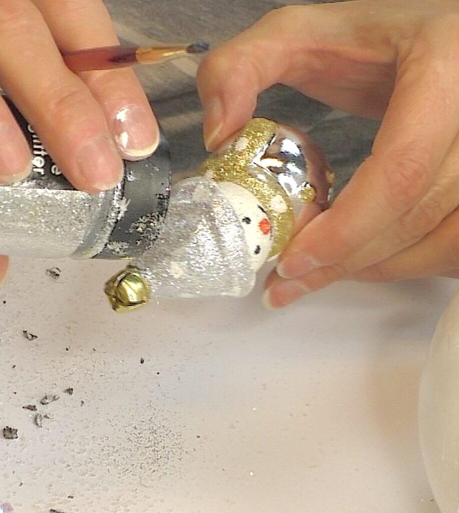Decorating a snowman ornament with silver glitter