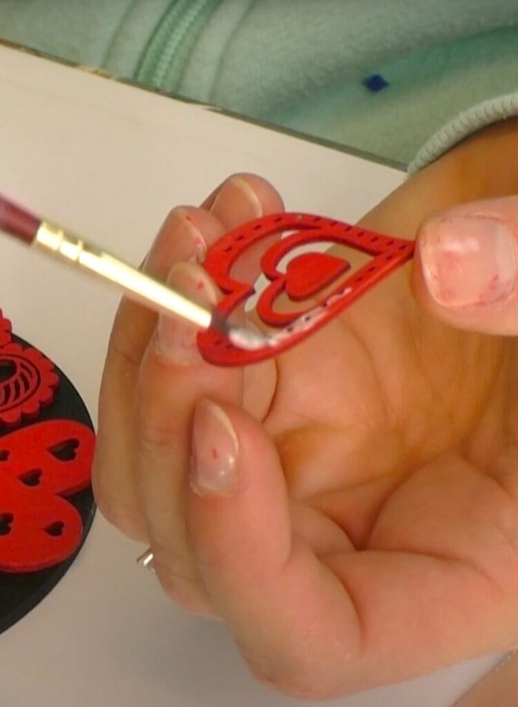 putting glue on the back of red wood hearts