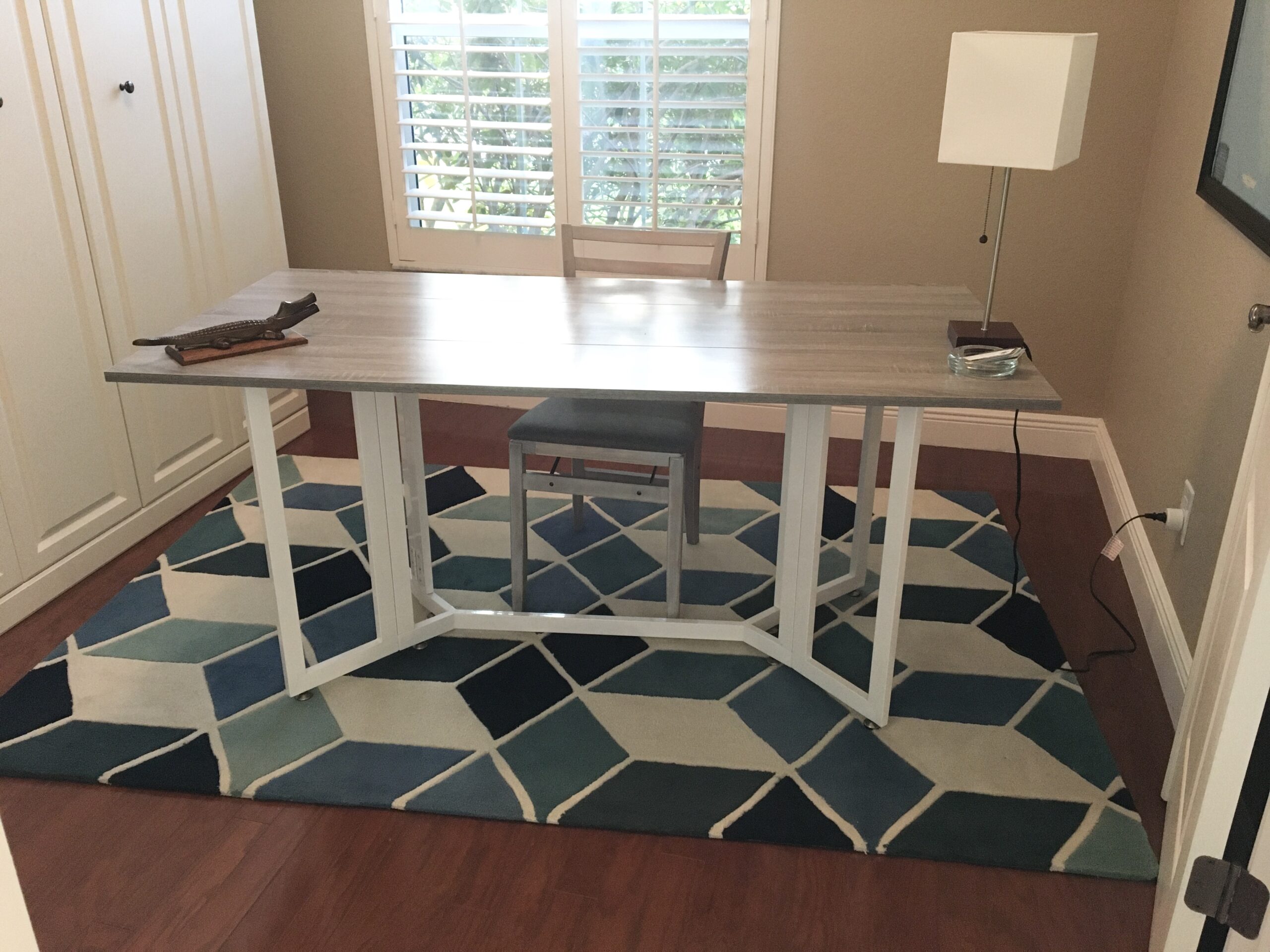 Folding gray top table with white legs used as a desk in home office.