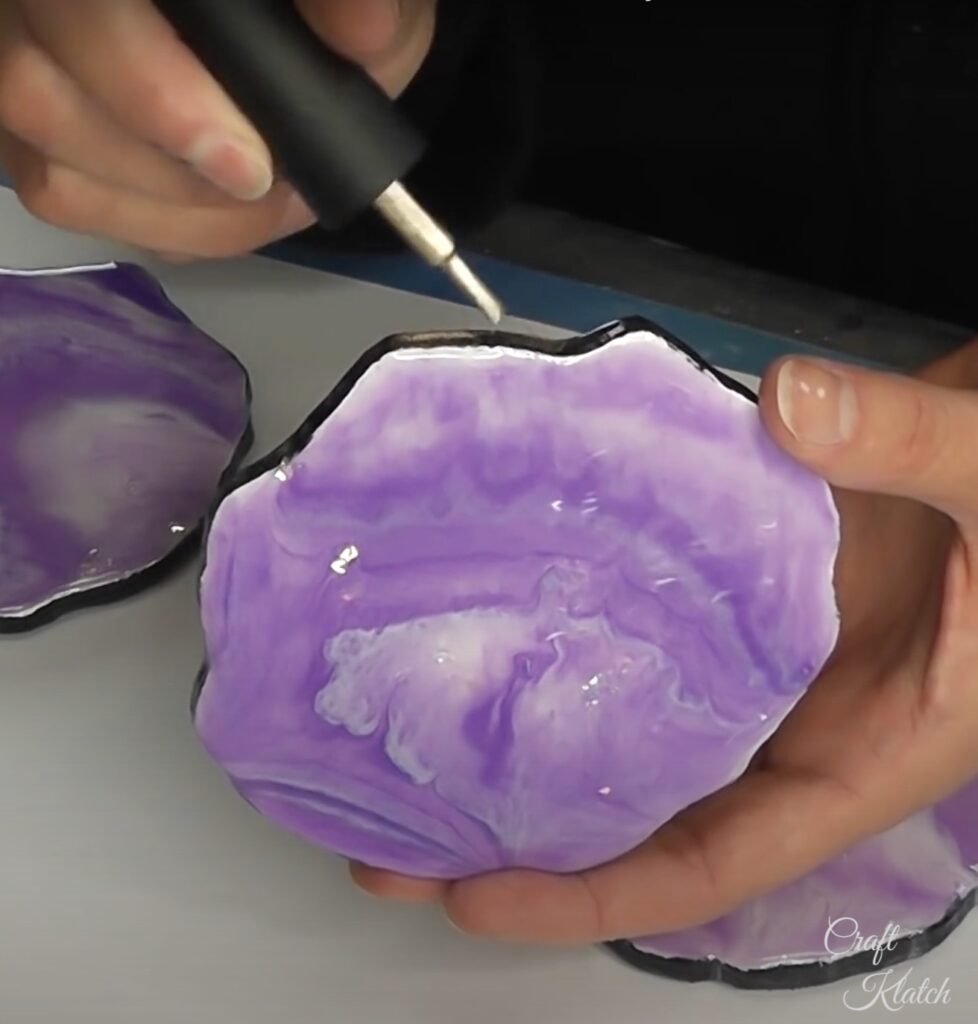 Painting gold nail polish on edge of purple and white resin geode coasters