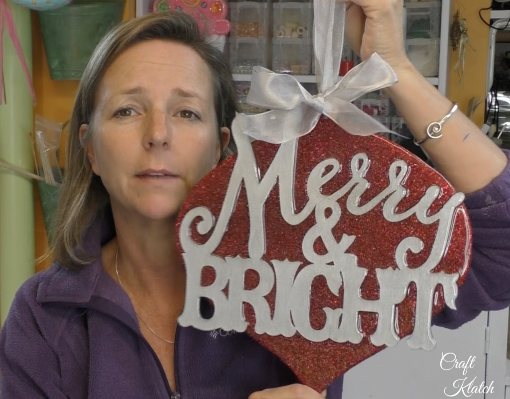 Mona of Craft Klatch holding up finished Dollar Tree ornament makeover Merry and Bright