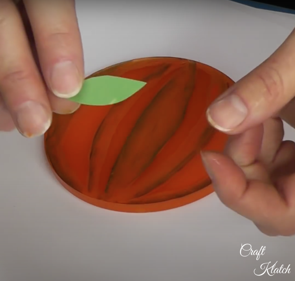 Holding a green leaf made out of construction paper for the pumpkin patch coaster