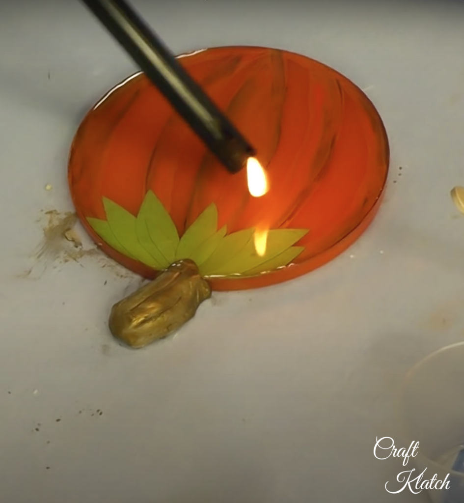 Using a lighter to pop bubbles on the pumpkin coaster