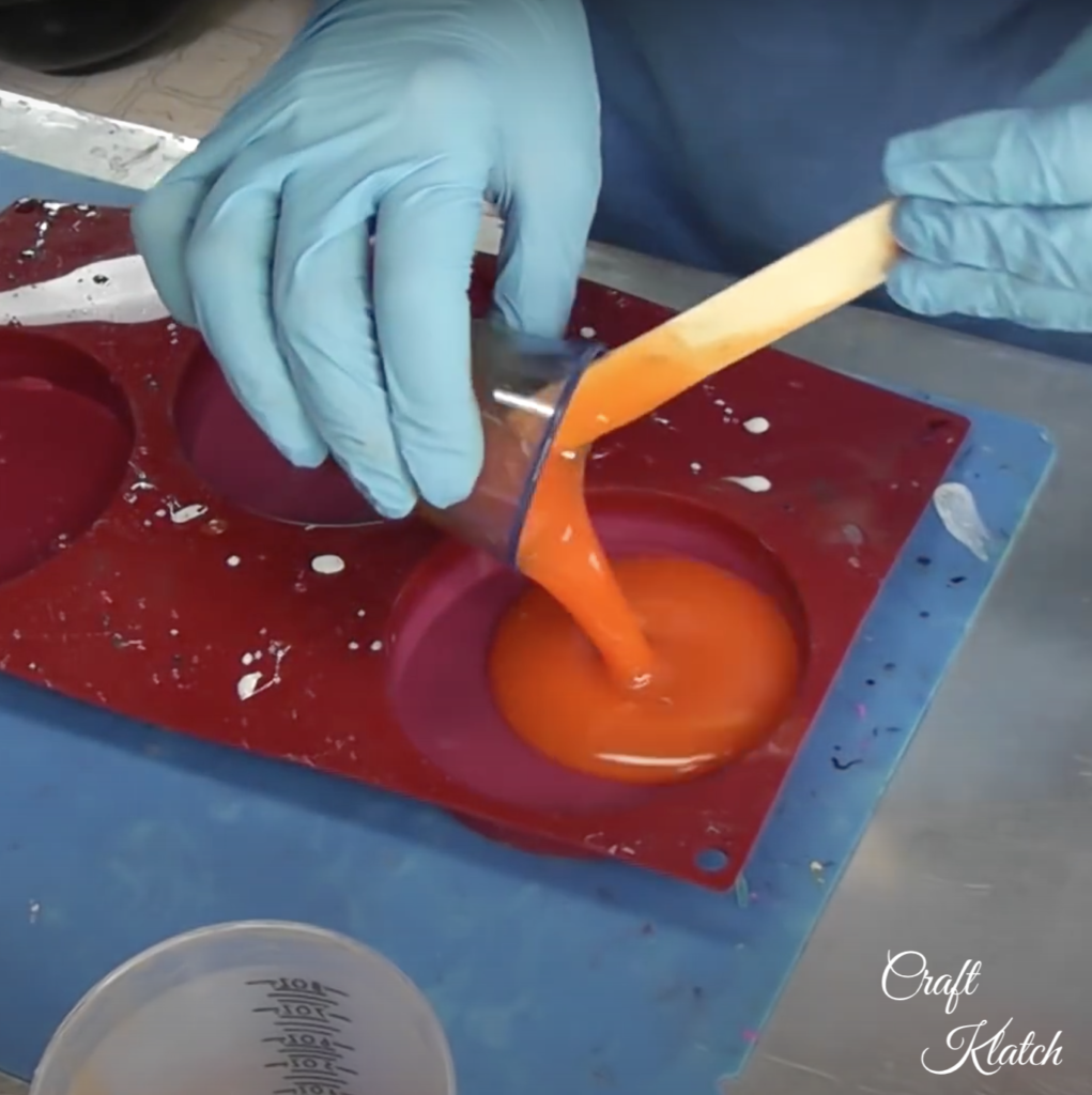 Pouring orange resin into coaster mold for pumpkin patch coaster