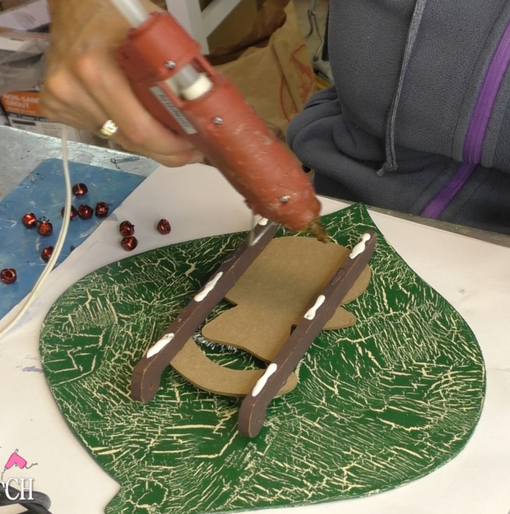 Glue being put on back of snowman sleigh embellishment