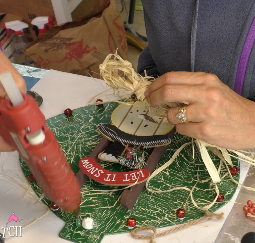 Gluing raffia bow on Christmas ornament