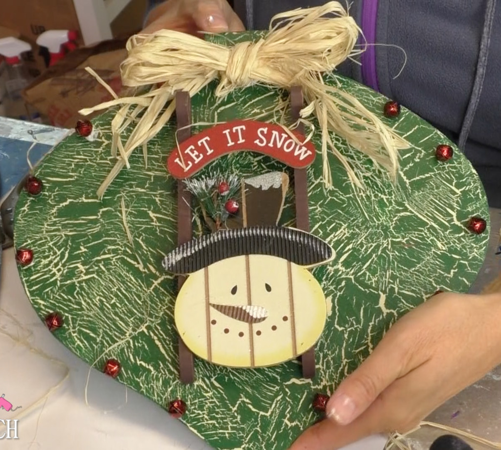 I found this ornament at Dollar Tree, in fact I found four! I decided I would style the ornament four different ways! This is the first and I'm going for a Rustic Snowman Christmas Ornament DIY! Dollar store crafts are a great way to decorate on a budget and customize your Christmas decorations to reflect your personal style and home decor ideas! #craftklatch #holidaydecorations #dollartree #dollartreecrafts #christmas #christmascraft #christmascraftideas #diy #craft #crafts #crafting #craftideas #howto #christmasdecor, Finished large Christmas ornament with snowman sled, red jingle bells and raffia bow