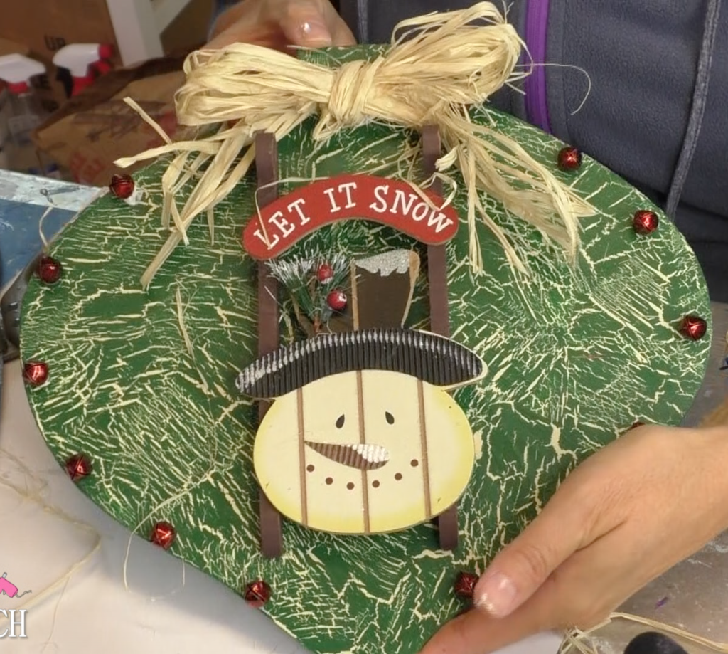 Finished large Christmas ornament with snowman sled, red jingle bells and raffia bow