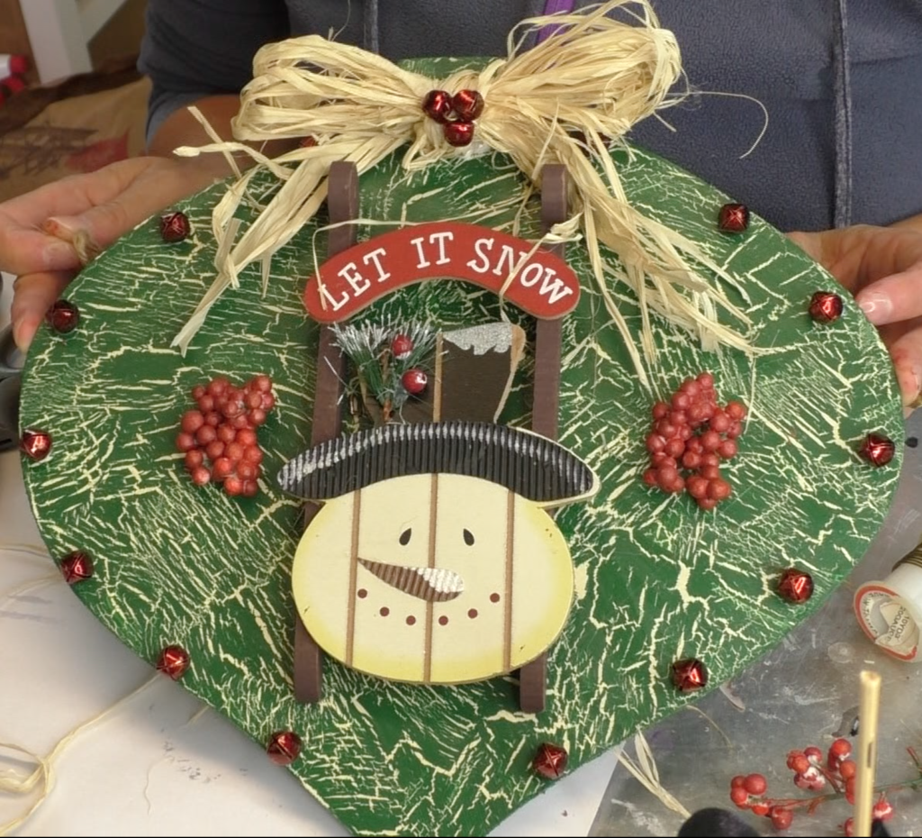 I found this ornament at Dollar Tree, in fact I found four! I decided I would style the ornament four different ways! This is the first and I'm going for a Rustic Snowman Christmas Ornament DIY! Dollar store crafts are a great way to decorate on a budget and customize your Christmas decorations to reflect your personal style and home decor ideas! #craftklatch #holidaydecorations #dollartree #dollartreecrafts #christmas #christmascraft #christmascraftideas #diy #craft #crafts #crafting #craftideas #howto #christmasdecor, Finished Christmas ornament with snowman sled, red jingle bells, red berries and raffia bow