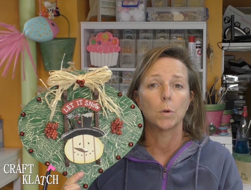 Dollar Tree Ornament Makeover #2 and this time we added glitz and glam to the Christmas decoration tutorial! A little resin and glitter make holiday art! Fun Christmas craft ideas! #craftklatch #craftideas #chiristmas #christmascrafts #resin #resinart #dollartree #dollartreecrafts #dollartreediys Mona holding up Christmas Dollar Tree ornament with snowman