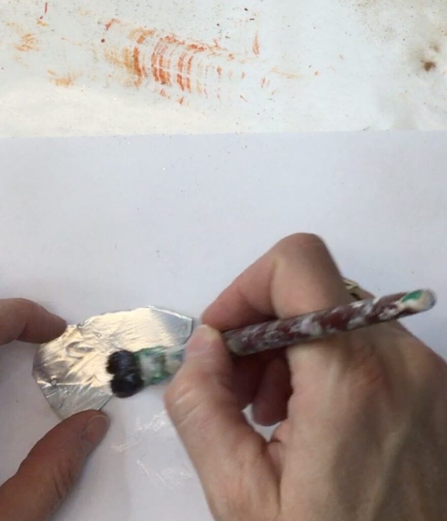 Brushing Mod Podge on metal leaf