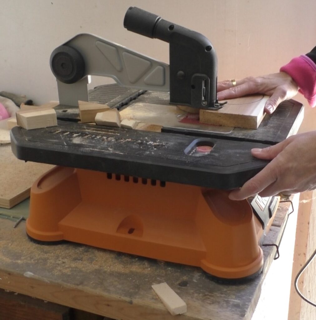 Using saw to cut pumpkin out of wood